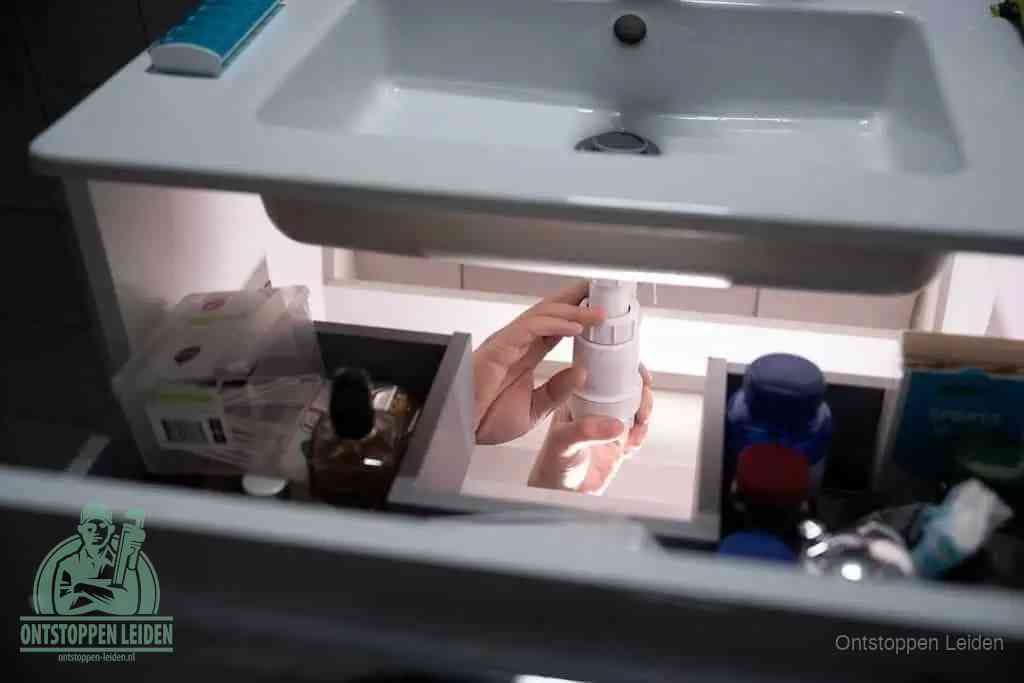 Een pompfles met zeep boven een wastafel, de heet water en afwasmiddel-methode om een vetprop in de afvoer los te maken in Leiden