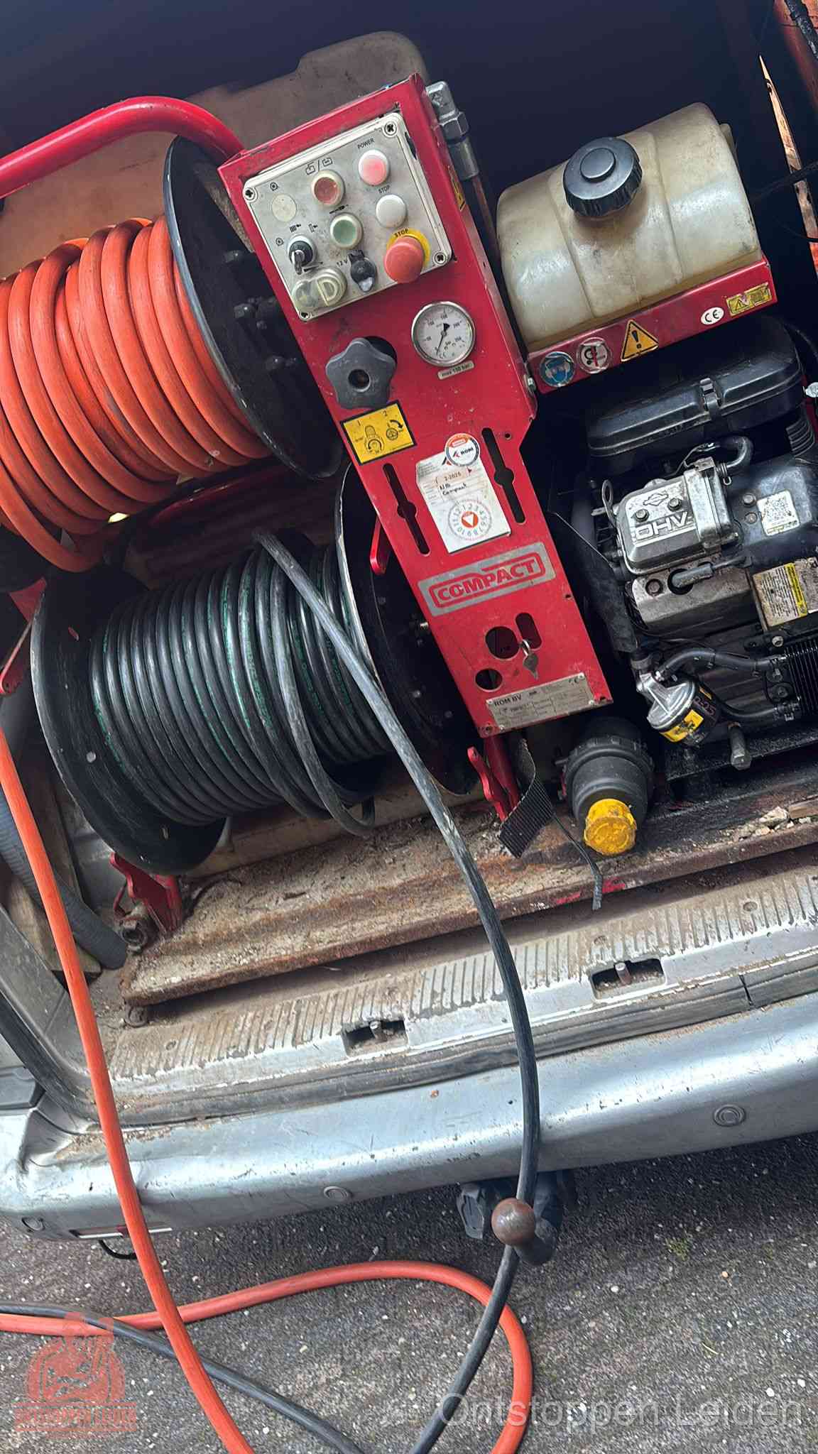 Een rood hogedruk-rioolreinigingstoestel met slangen in de laadbak van de bedrijfsbus, apparatuur voor een hardnekkige wc-verstopping in Leiden