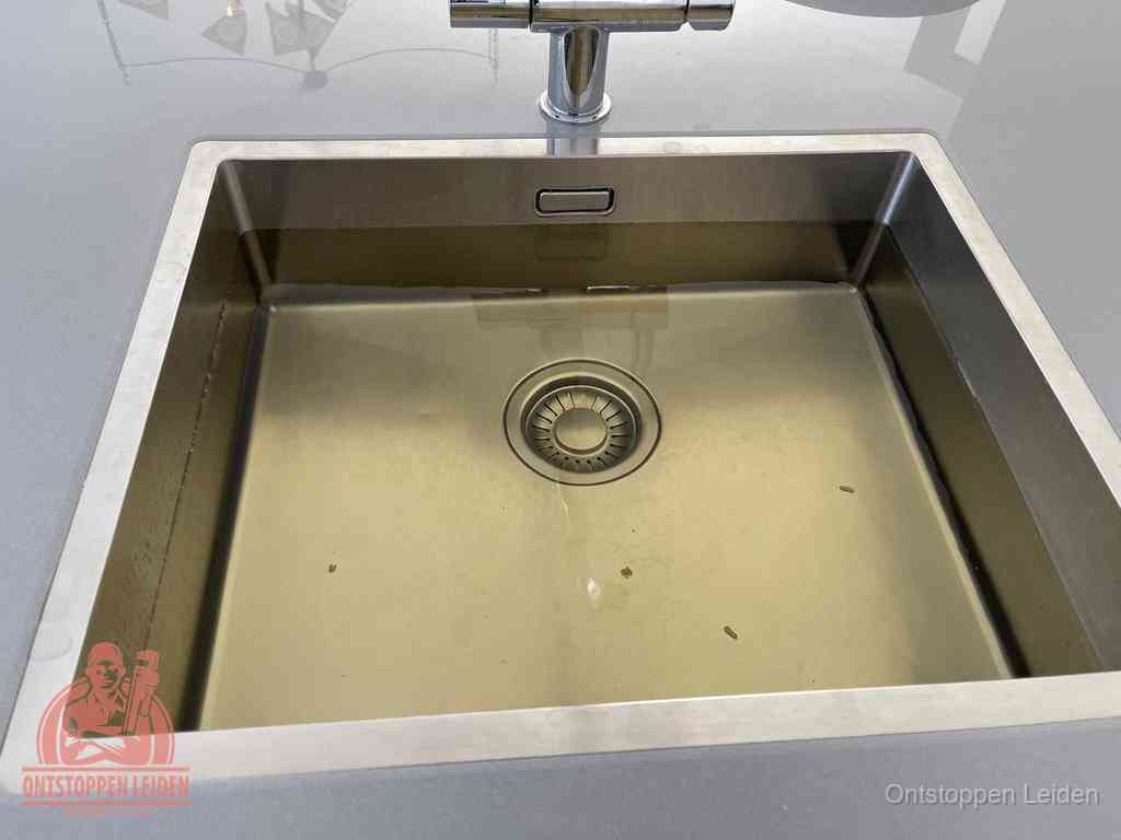 Stilstaand water in een rvs spoelbak dat niet wegloopt, een duidelijk signaal van een gootsteenverstopping in Leiden