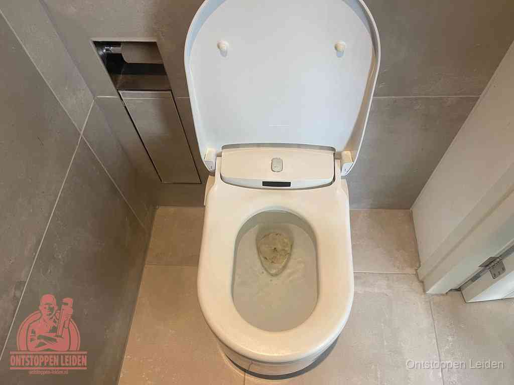 Een wit hangtoilet waarin een prop wc-papier op het water blijft drijven, een duidelijk signaal van een verstopte wc in Leiden