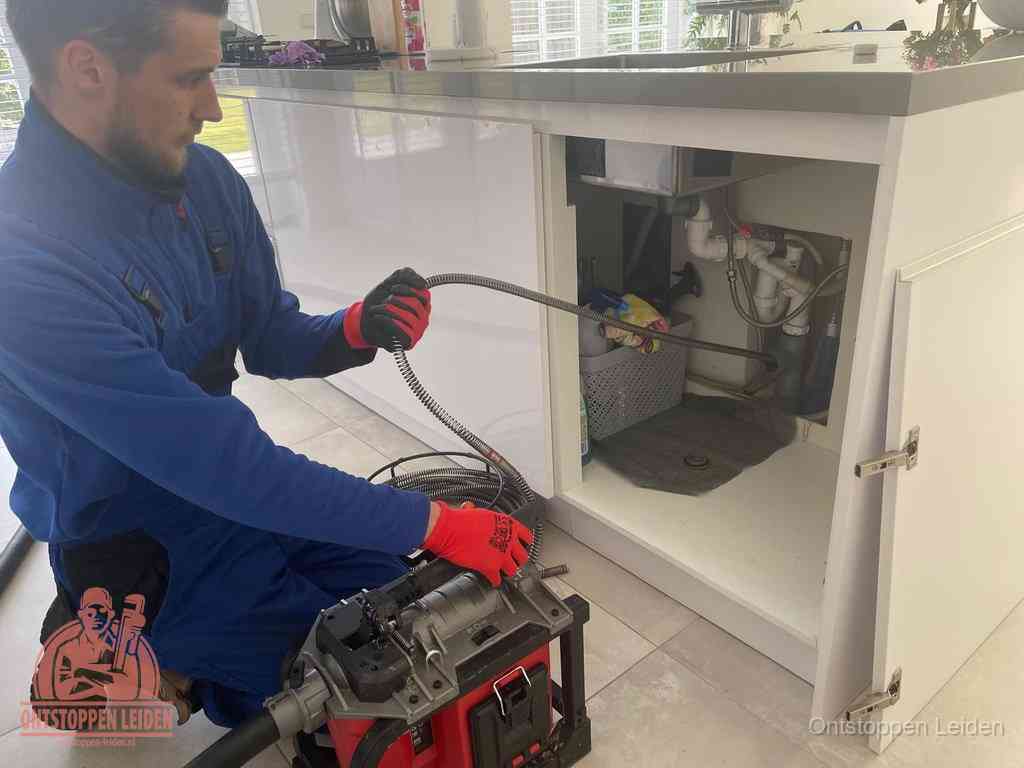 Een monteur reinigt de keukenafvoer grondig met een veermachine om terugkerende gootsteenverstoppingen te voorkomen in Leiden
