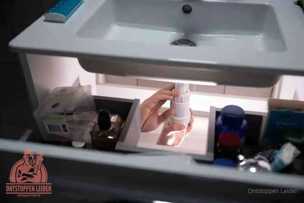 Een pompfles met zeep boven een wastafel in de toiletruimte, de warm water en afwasmiddel-methode om de wc te ontstoppen in Leiden